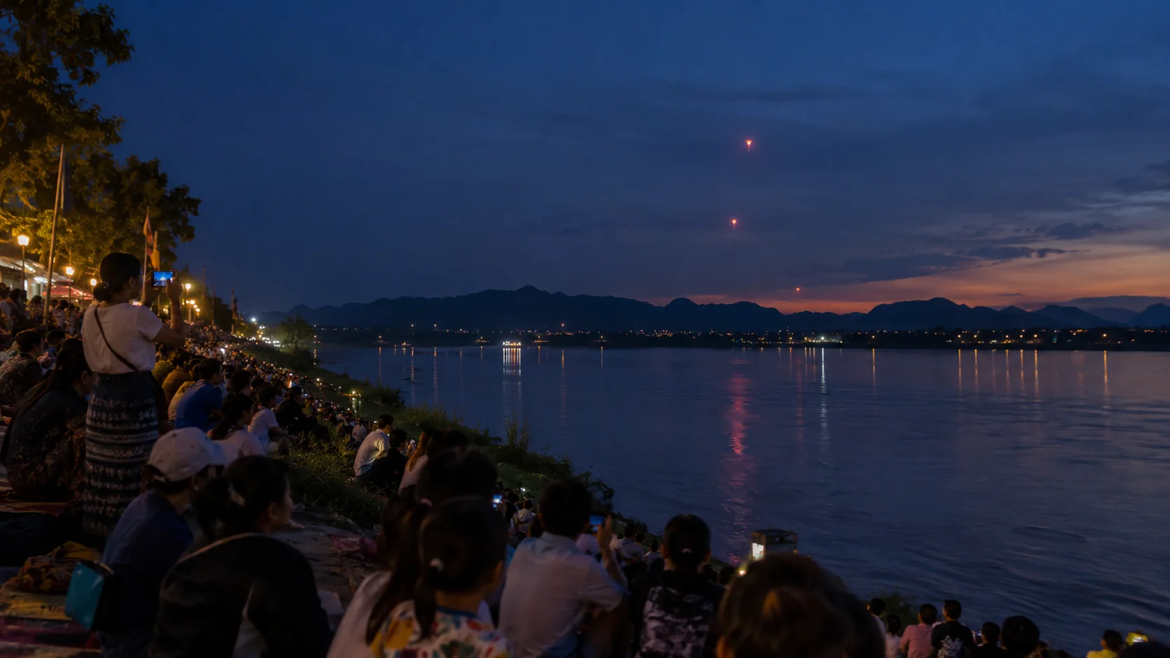 Crowds watching Naga fireballs rise over the Mekong at dusk