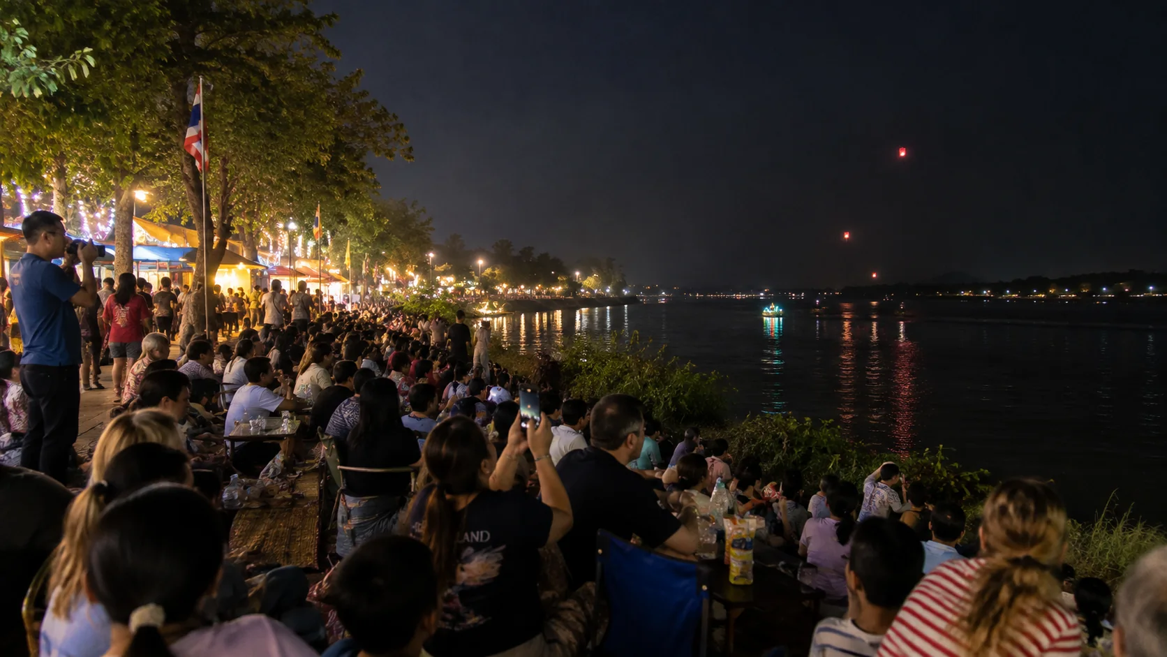 Crowd watching fireballs rise over the Mekong at night