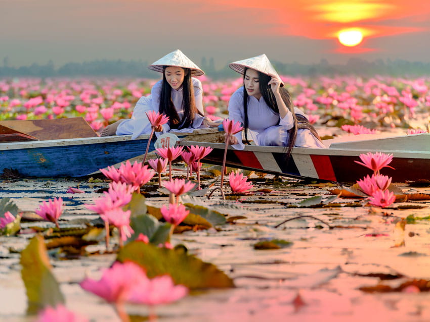 Two Asian Women in national Costume Sitting in Canoes and Enjoying the Red Lotus Lake Udon