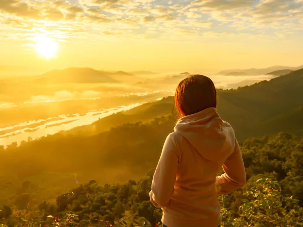 A woman watching a misty sunrise over the Mekong River during Isan Winter at Udon Thani, Northeast Thailand.