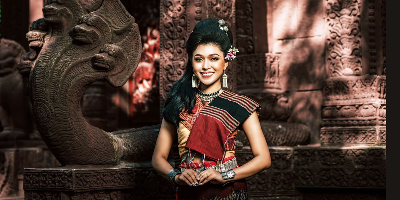 Young female woman wearing traditonal Isan dress waits to greet guests arriving at Nakara Villas & Glamping