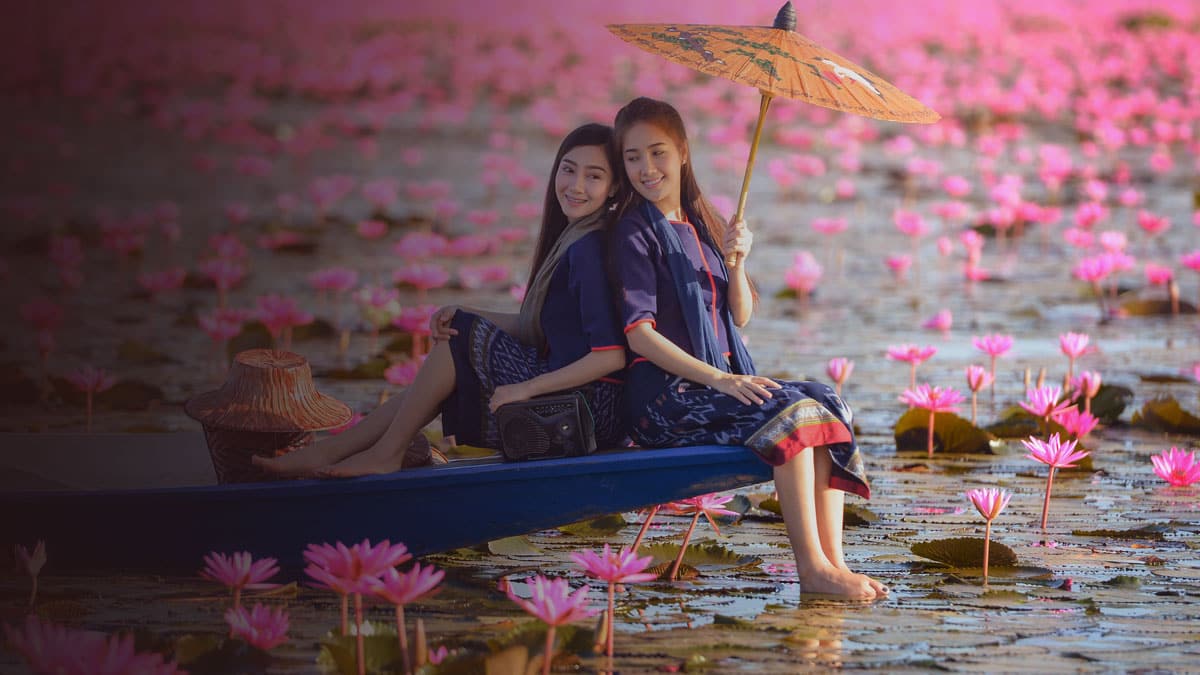 Young Women Wearing Traditional Thai Costumes Riding in a Blue Canoe Enjoying Morning on the Red Lotus Lake Udon Thani