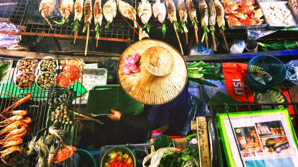 A Thai Woman prepares Isan Street food including grilled fish, jumbo prawns and crabs