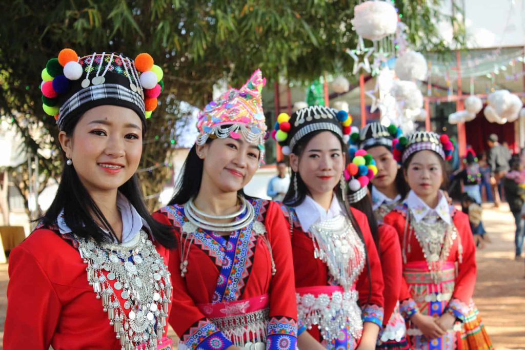 Young Women from Laos in traditional red dresses and elaborate headgear seen on day trip from Nakara Villas and Glamping
