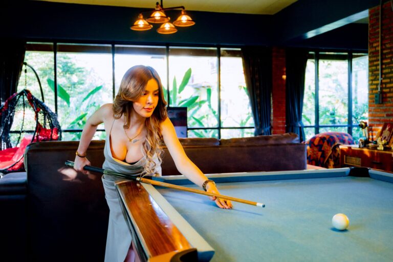 A beautiful women with ample cleavage if leaning over a pool table at Nakee Villa part of Nakara Villas and Glamping